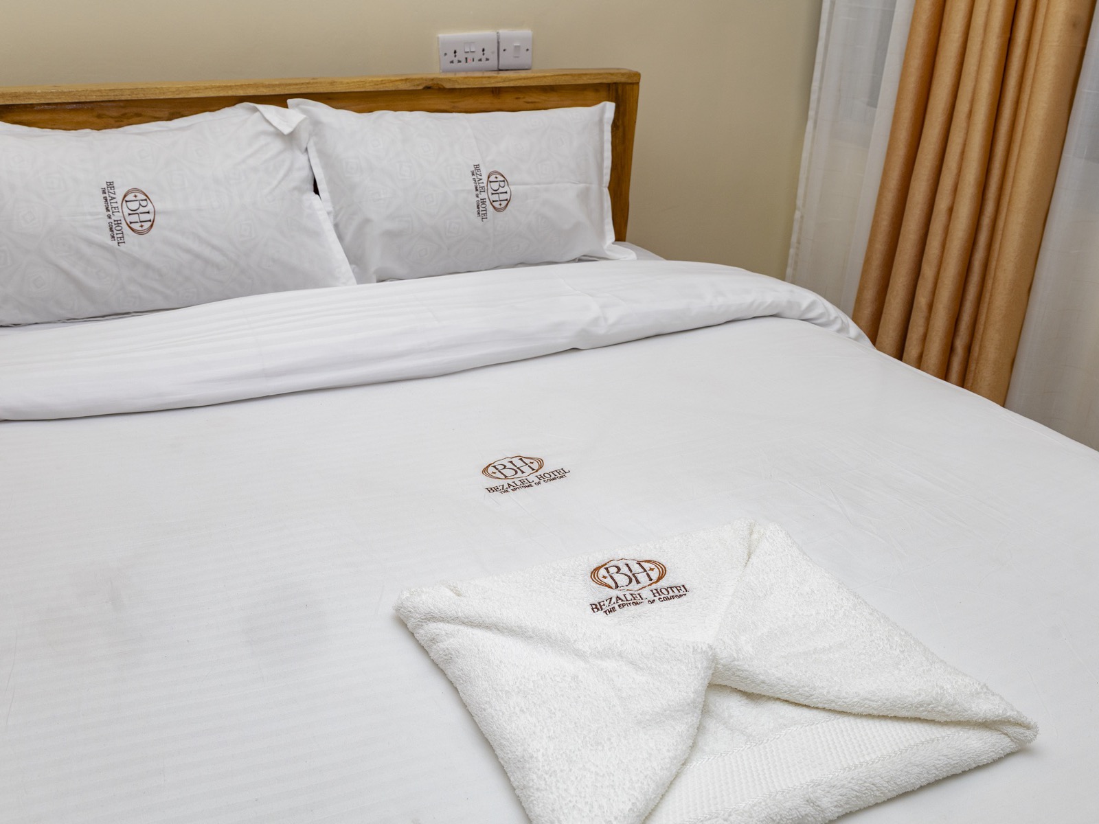 The double bed from the foot, with the monogrammed pillows
